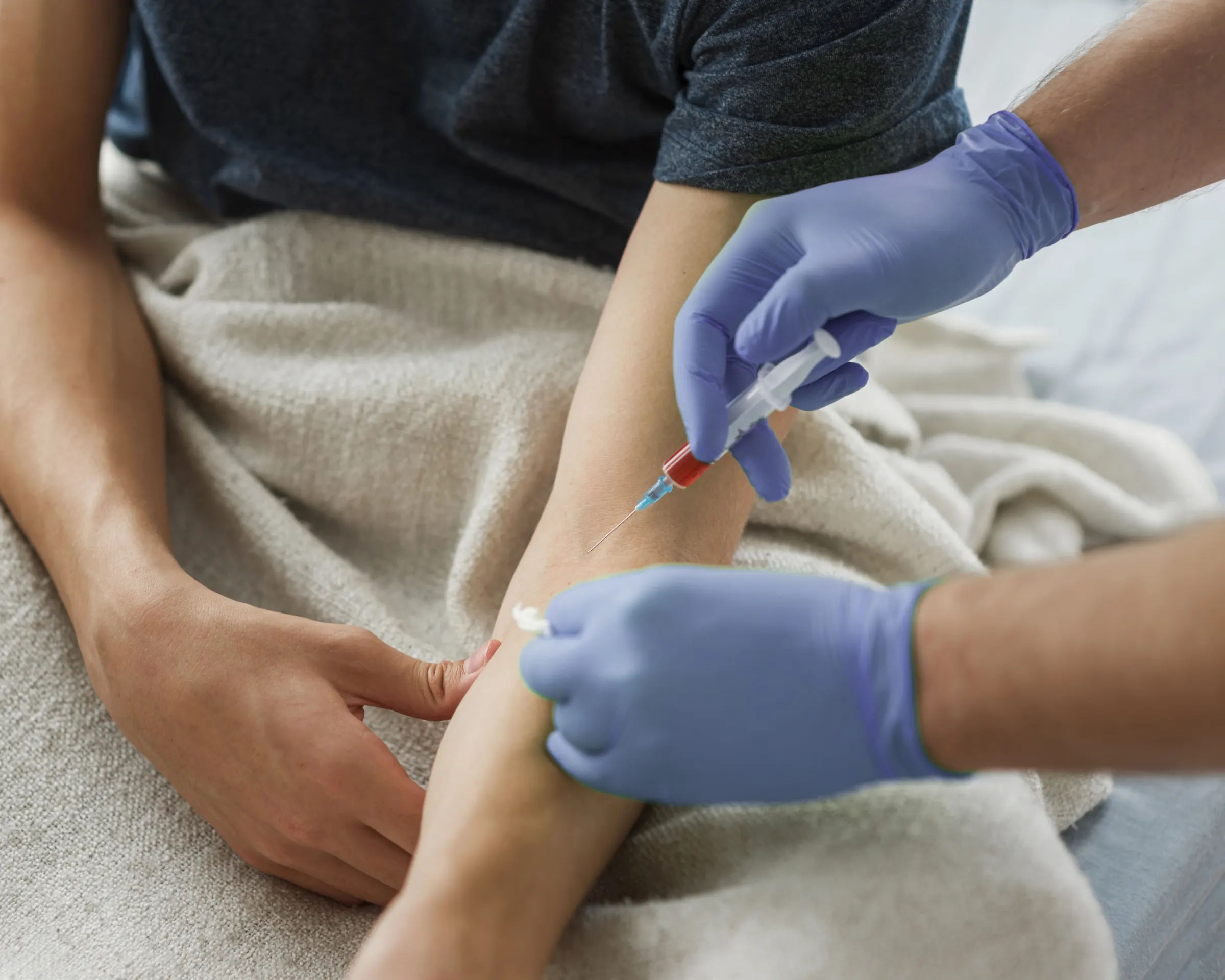 Un prelievo di sangue a casa: l'operatore con i guanti e il braccio del paziente